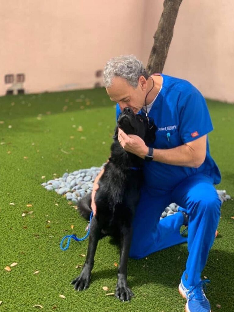 Central Broward doctor kissing a black dog on the nose outside the hospital